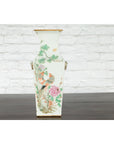Dark wood Qing 19th c. altar vase with hand-painted flowers and birds, in front of a white brick wall.