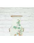 Blue and white porcelain Qing dynasty altar vase with hand-painted flowers and birds, against a white brick wall.