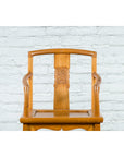 Brown elmwood Qing Dynasty armchair with hand-carved medallion, placed in front of a white brick wall.