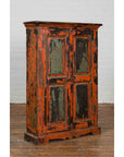 Hand-painted burnt orange and green wood cabinet, 19th century, on wooden floor next to white brick wall.