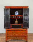 Black lacquer cabinet with black doors, inside displaying a blue-and-white vase and a small golden Buddha statue.