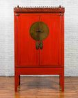Red lacquered wood Qing Dynasty wedding cabinet with carved panels and brass hardware, four-legged, 19th century.