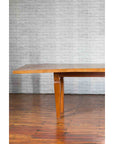 Brown mango wood vintage Indonesian dining table with tapered legs on polished wooden floor, full view.