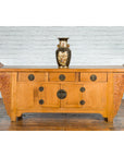 Natural wood Qing Dynasty sideboard with carved spandrels, three drawers, and a vase on top.
