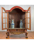 Gilded wood Dutch Colonial cabinet with bonnet top and glass doors, two blue-and-white vases inside, early 20th century.
