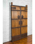 Brown wood Qing Dynasty palace doors with iron fittings, set against a white brick wall and wooden floor.
