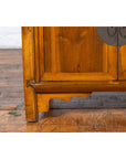 Close-up of brown elmwood Chinese side chest from early 20th century with carved details and bronze medallion hardware.