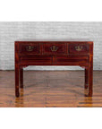 Dark red wood Chinese antique console table with drawers, horse hoof legs, against a white brick wall.