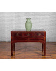 Green ceramic vase on Chinese antique console table with drawers, horse hoof legs, and dark red patina.