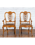 Dark wood Chinese Qing Dynasty 19th century armchair with carved medallion, on wooden floor by white brick wall.