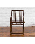Elmwood Chinese Qing Dynasty 19th century armchair with slatted back and arms, beside white brick wall on wood floor.