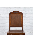 Brown wooden Qing Dynasty side chair with rattan accents, 19th century, in front of a white brick wall.