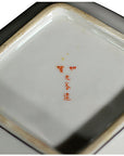 Close-up of ceramic Japanese plates base with red characters and floral corner design.
