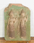Green carved stone Thai temple wall plaque with ceremonial dancers, ornate headdresses, and raised hands, close-up view.