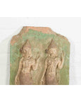 Faded green stone wall plaque with Thai ceremonial dancers, carved in relief, close-up view.