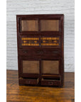 Brown wood Japanese tansu cabinet with sliding doors and drawers, early 20th century, set against a brick wall.