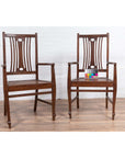 Brown wood Dutch Colonial armchairs with pierced back splats, side by side on a wooden floor.