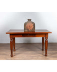 Brown ceramic jug with sun motif on antique Dutch Colonial Javanese teak desk with turned legs.