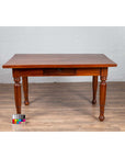 Brown teak antique Dutch Colonial Javanese desk with single drawer and turned legs on wood floor, color chart nearby.