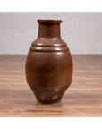 Brown glazed ceramic 19th-century Japanese Tamba Tachikui water jug on wooden surface against light wall.