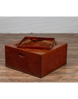 Brown Keyaki wood rectangular hibachi with copper liner on wooden floor against white brick wall.