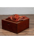 Rectangular keyaki wood hibachi with copper liner on wooden floor against white wall, Japanese 19th century.
