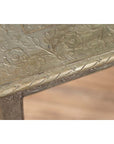 Close-up of silver overlay Indian vintage metal coffee table with intricate floral and leaf engravings.