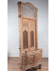 Natural wood balcony with hand-carved foliage motifs and bonnet top, inspired by antique Indian windows.