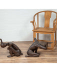 Bronze kneeling table bases on wooden floor beside bronze coffee table base, vintage style furniture set.