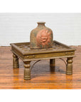 Close-up of a ceramic sun face vase on an Indian geometric brass-sheathed coffee table with ornate legs.