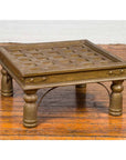 Brass-sheathed geometric Indian window grate repurposed as a coffee table with grid top design.