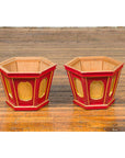 Gold and red lacquer Japanese Taishō hexagonal planters with reeded cartouches on a wooden floor.