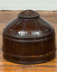 Dark patina wooden Chinese antique with decorative cover and unusual shape on a wooden floor.
