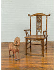 Brown antique wooden armchair next to a small vintage Indian rust-carved horse from Madras on polished wood floor.