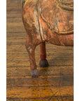 Close-up of a rust-colored carved wooden horse figurine from Madras on a scratched floor.