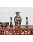 Close-up of two cobalt blue hand-painted Chinese candlesticks with cartouches on a carved table by a white brick wall.