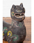 Polychrome carved wood mythical guardian animal, antique Northern Thai Chiang Mai, on wooden floor by white wall.