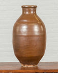 Close-up of a brown ceramic Japanese Meiji period 19th-century water jar with monochrome patina on wooden surface.