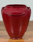 Oxblood ceramic oversized Thai water jar with rope design from Chiang Mai on a wooden floor.