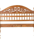 Brown carved wood Indonesian headboard with scrolling foliage and petite balusters, white background.