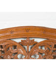 Close-up of vintage carved wood Indonesian headboard with scrolling foliage and petite balusters on white background.