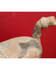 Terracotta Chinese Han Dynasty horse statue against a solid red background.