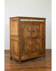 Wooden Indonesian cabinet with sunburst design and blue tile accents, displayed on a wooden floor.