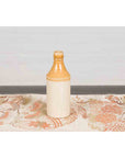 Yellow and cream ceramic Chinese flask on a floral tablecloth against a plain background.