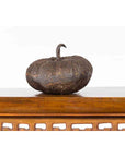 Bronze pumpkin sculpture with rustic patina on a wooden table, white background, contemporary style.