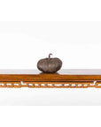 Bronze pumpkin sculpture with rustic patina on wooden shelf, white background, contemporary lost wax style.