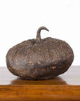 Bronze pumpkin sculpture with rustic patina on wooden surface, white background, contemporary lost wax design.