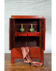 Red lacquer Qing Dynasty 19th c. cabinet with gilded chinoiserie, open doors showing two green vases and pink fabric.