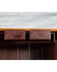 Close-up of a wooden Qing Dynasty cabinet with chinoiserie panels, two drawers open, set against a white brick wall.