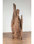 Brown driftwood carving from Northern Thailand on wooden floor against a white brick wall, Chiang Mai style decor.